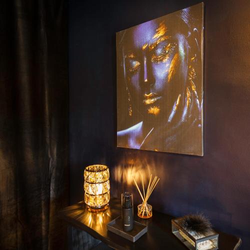 une table avec une lampe et une peinture sur le mur dans l'établissement Le Carré Rose - Love Room proche de Rennes, à Guichen