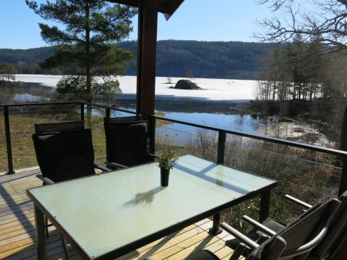 a table and chairs on a porch with a view of a lake at Holiday Home Øydnablikk by Interhome in Byremo