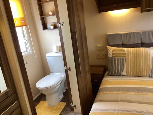 ein kleines Bad mit WC und ein Bett in der Unterkunft Luxury caravan at Seton Sands in Port Seton