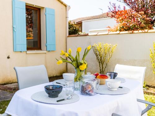 Una mesa blanca con un jarrón de flores. en Holiday Home Les Privileges by Interhome, en Saint-Palais-sur-Mer