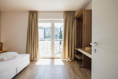 een slaapkamer met een bed en een groot raam bij Lake Side Suites in Riva del Garda
