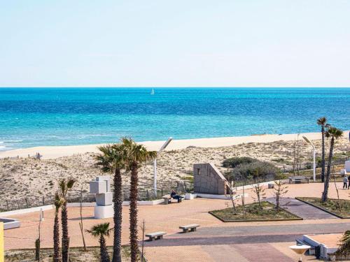 - une plage avec des palmiers, un bâtiment et l'océan dans l'établissement Studio Vistaéro-6 by Interhome, au Barcarès