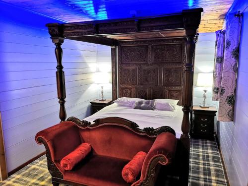 1 dormitorio con cama con dosel y sofá en Magpie 5 Hot Tub HuntersMoon-Warminster-Bath-Wiltshire en Warminster