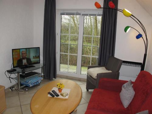 a living room with a red couch and a tv at Apartment Gollwitzer Park - Insel Poel-3 by Interhome in Gollwitz