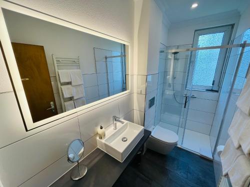 ein Badezimmer mit einem Waschbecken, einem WC und einem Spiegel in der Unterkunft Ferienwohnung am Eberbach in Stadtoldendorf