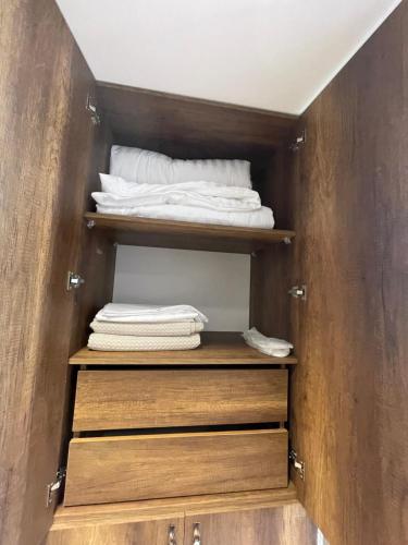 a closet with wooden shelves and white towels at Hotel Kroi near castle entrance castle and town view in Krujë
