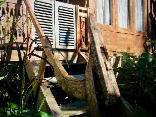 a wooden chair sitting in front of a building at D'Ume Bendoel Homestay in Jatiluwih