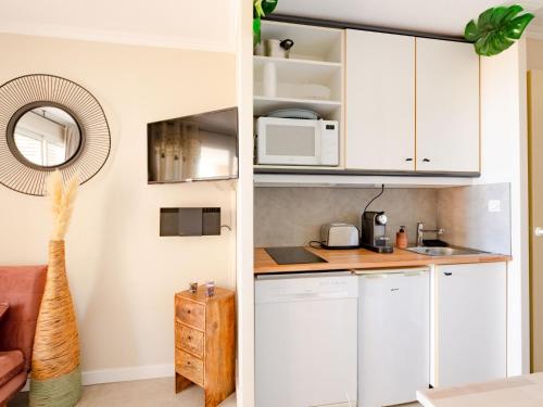 une cuisine avec des armoires blanches et un micro-ondes dans l'établissement Apartment L'Esquinade - G3 033 by Interhome, à Agay