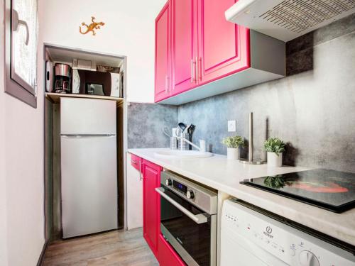 een keuken met rode kasten en een witte koelkast bij Apartment Les Villageoises-3 by Interhome in Le Barcarès