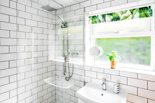 a white tiled bathroom with a shower and a sink at Laurel Cottage in Lincolnshire