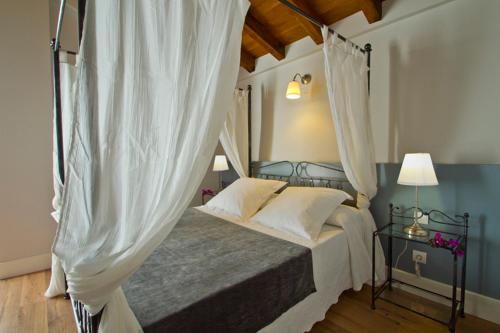 a bedroom with a canopy bed with white curtains at Villa Arce Hotel in Puente Viesgo