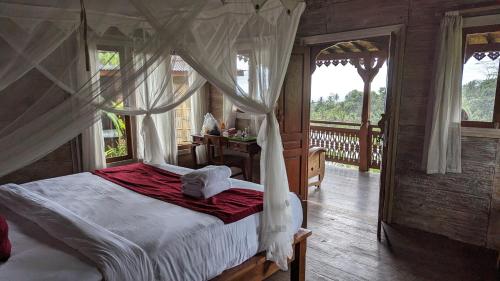 1 dormitorio con cama con dosel y balcón en D'Ume Bendoel Homestay en Jatiluwih