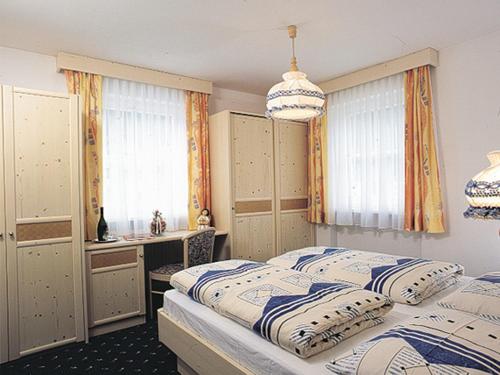 a bedroom with two beds and a desk and windows at Appartmenthotel Residence Elvis in Ortisei