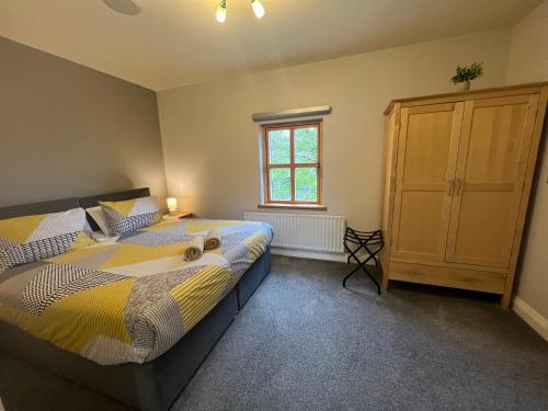 a bedroom with a bed and a cabinet and a window at 2 Castle Hume Court Holiday House in Enniskillen