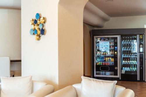 a drink refrigerator in a room with white couches at Hotel dP Olbia - Sardinia in Olbia