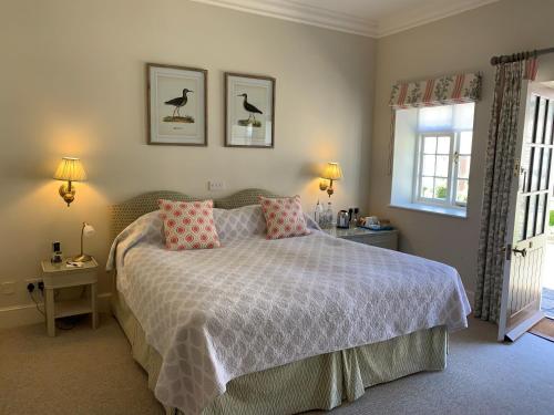 a bedroom with a bed with pink pillows and a window at Plumber Manor Hotel in Sturminster Newton