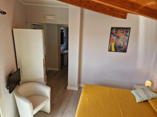a bedroom with a bed and a chair and a painting at Ca'Mea in Villasimius