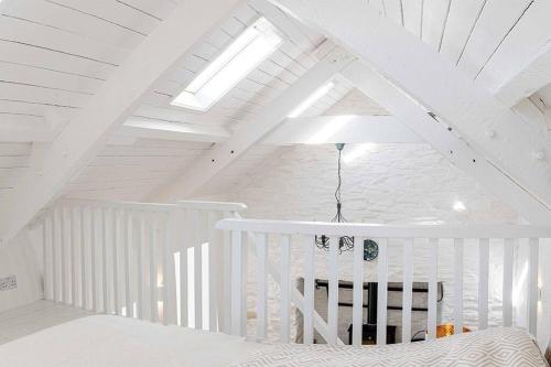 ein weißes Dachzimmer mit einem Bett und einer Decke in der Unterkunft Gemütliches Cottage mit Meerblick in Ballydehob