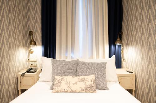 a bedroom with a white bed with two night stands at Hotel Cetina Palacio de los Salcedo in Baeza
