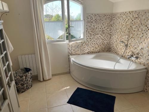 une baignoire blanche dans une salle de bain avec une fenêtre dans l'établissement Maison de charme avec piscine, à Saint-Martin-de-Seignanx