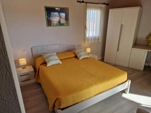 a small bedroom with a bed with a yellow blanket at Ca'Mea in Villasimius