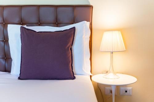a bed with a purple pillow next to a lamp at Boccioleto Resort - Place of Charme in Montaione