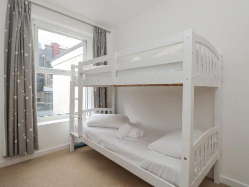 a white bunk bed in a room with a window at 2 North Furzeham Road in Brixham