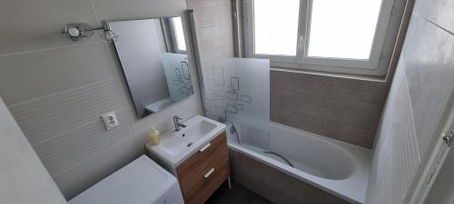 a bathroom with a sink and a tub and a mirror at Logement refait à neuf - Clim & Parking privé in Montpellier