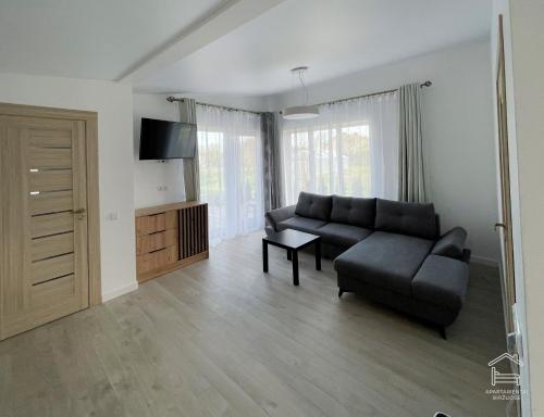 a living room with a black couch and a tv at Apartamentai Biržuose, Cozy Modern Bungalows in Biržai
