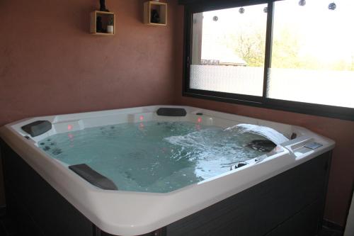 eine große Badewanne in einem Zimmer mit Fenster in der Unterkunft Happy & Relax in Mentque-Nortbécourt