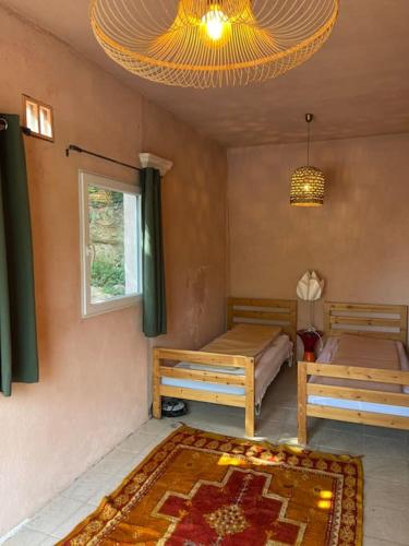 Cette chambre comprend 2 lits, une fenêtre et un tapis. dans l'établissement Villa de qualité vue mer piscine chauffée, à Roquebrune-sur Argens