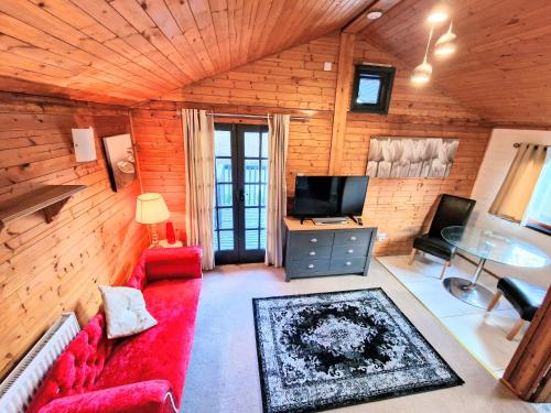 ein Wohnzimmer mit einem roten Sofa und einem TV in der Unterkunft Otter 4 Hot Tub - HuntersMoon-Warminster-Bath-Salisbury in Warminster