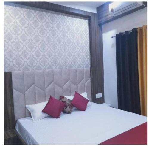 Un dormitorio con una cama blanca con almohadas rojas y moradas en The A Cube Inn, en Bokāro