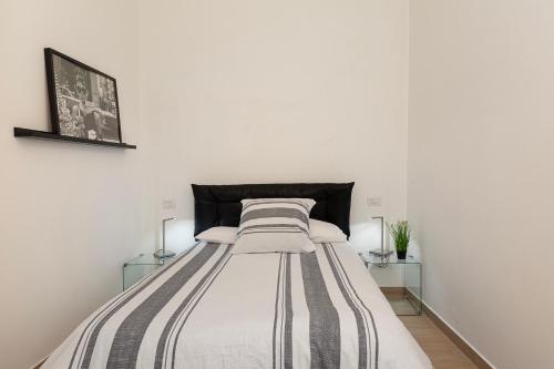 a bed in a white room with two tables at Old Town Pavia in Pavia