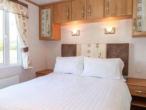Un dormitorio con una cama con sábanas blancas y una ventana. en Whiteside, en Cockermouth