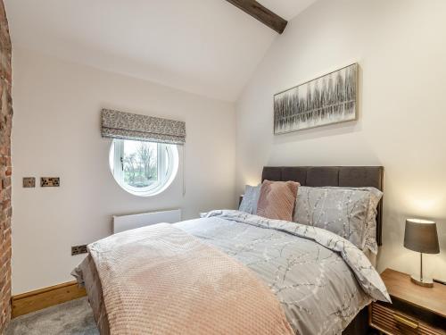 a bedroom with a bed and a window at Barn One in Sandbach