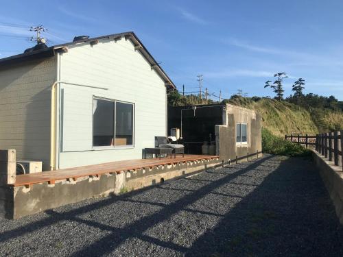 a white house with a fence next to it at Villa Thalassa 貸切 in Oshima