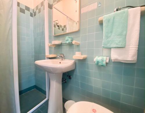 baño de azulejos azules con lavabo y aseo en Hotel Villa Grazia, en Cesenatico