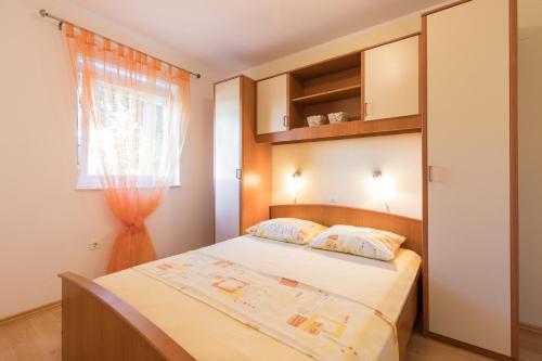 a small bedroom with a bed and a window at Apartments Mirjana * central location and close to beach in Punat