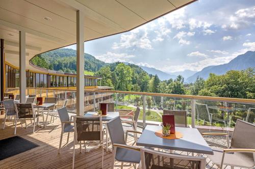 a restaurant with tables and chairs on a balcony with mountains at Vivea Hotel Bad Goisern in Bad Goisern