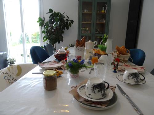 a table with plates and cups on top of it at Maison d'hôtes les roses trémières in Saclay