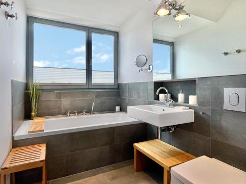ハイリゲンハーフェンにあるOstsee - Reetdachhaus Nr 5 "Beaufort" im Strand Resortのバスルーム(バスタブ、シンク付)、窓が備わります。