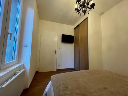 a bedroom with a bed and a window and a chandelier at Appartement cosy centre ville in Roanne