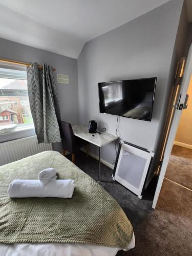 Habitación de hotel con cama, escritorio y TV. en Fox Hollies Shared House en Birmingham
