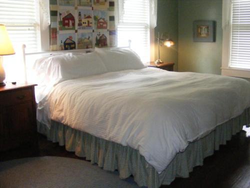 a bedroom with a bed with white sheets and a window at PriceHouseInn in Glen Rose
