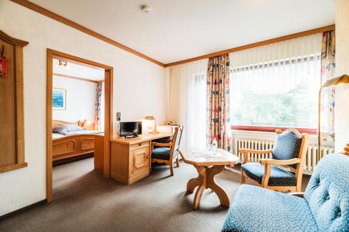 ein Hotelzimmer mit einem Schreibtisch und einem Schlafzimmer in der Unterkunft Landhotel Alte Aue in Altenau