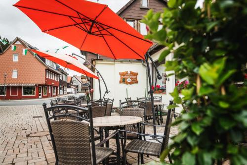 a group of tables and chairs with red umbrellas at Landhotel Alte Aue in Altenau
