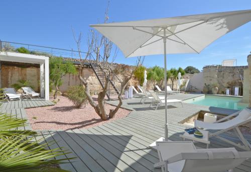 a patio with chairs and an umbrella and a pool at Villa Rocce Bianche in Favignana