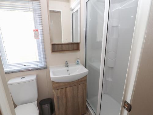 La salle de bains est pourvue de toilettes, d'un lavabo et d'une douche. dans l'établissement Rhodes Retreat, à Cockermouth