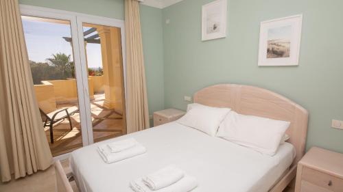 ein Schlafzimmer mit einem Bett mit weißen Kissen und einem Balkon in der Unterkunft Majestic Hills 1 5 in Casares